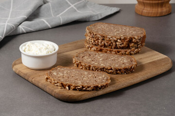 Delicious whole grain bread topped with creamy cottage cheese on a wooden board in a modern kitchen setting
