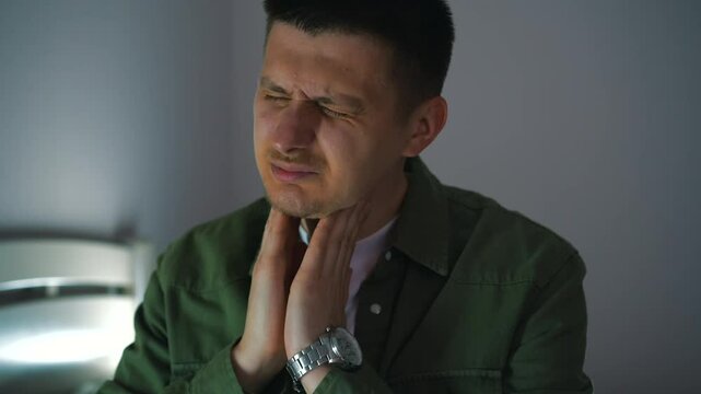 A guy with European appearance touches his sore throat.
The man has a cold and is suffering from a sore throat.
It hurts for a person to swallow.
Redness in the throat.
Infection, sore throat, pain