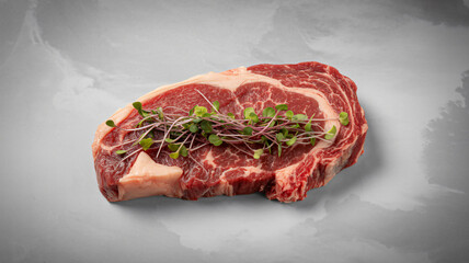 Raw marbled beef steak with microgreens on a gray background