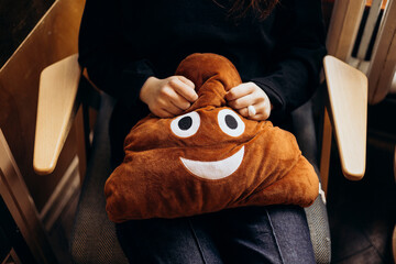 Young person sitting with a plush poop emoji pillow