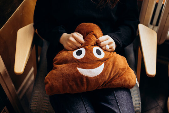Young person sitting with a plush poop emoji pillow