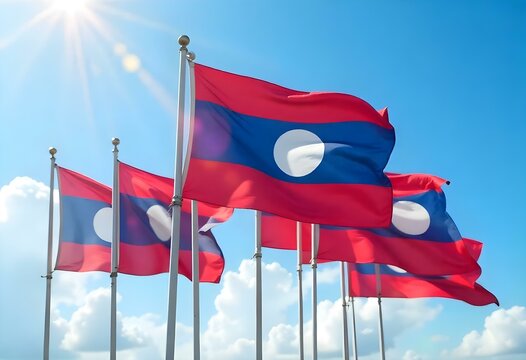 Realistic digital painting of multiple Laos flags waving in the wind under a bright, sunny sky. Each flag shows the red, blue, and white circle design clearly. The flags are arranged on tall poles,