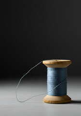 Light grey wooden spool of blue thread