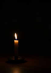 Single candle flame in dark room