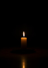 Single candle flame in darkness