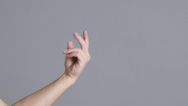 Footage of a hand snapping its fingers against a grey background.