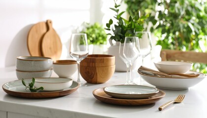Fototapeta premium collection of stylish kitchenware arranged on a marble countertop, including ceramic plates, wooden utensils, and glassware. Soft natural light from a nearby window, creating gentle reflections and s