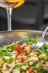 Delicious gnocchi with mushrooms, sun-dried tomatoes, arugula, and pine nuts