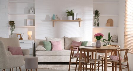 Stylish dining table with chairs and comfortable sofa in room. Interior design