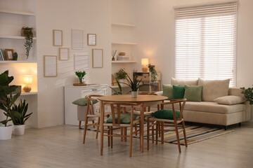Stylish dining table with chairs and comfortable sofa in room. Interior design