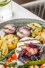 Grilled vegetables and melted cheese with berry sauce on a plate. Grilled brie or camembert with jam