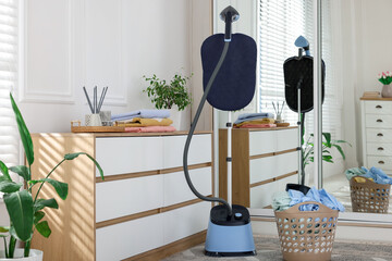 Modern upright steamer and basket with clean laundry indoors