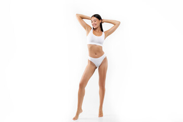 Slim lady posing in white underwear with hands behind her head isolated over white studio background, showing beautiful fit body, full length