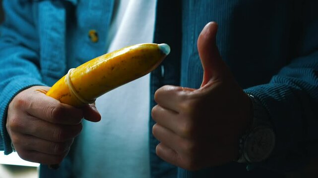 A man with a banana and a condom shows how to protect himself from unwanted pregnancy and sexually transmitted infections.
Aborted pregnancy.
Safe sex.
Intimacy, pregnancy, abortion, sex