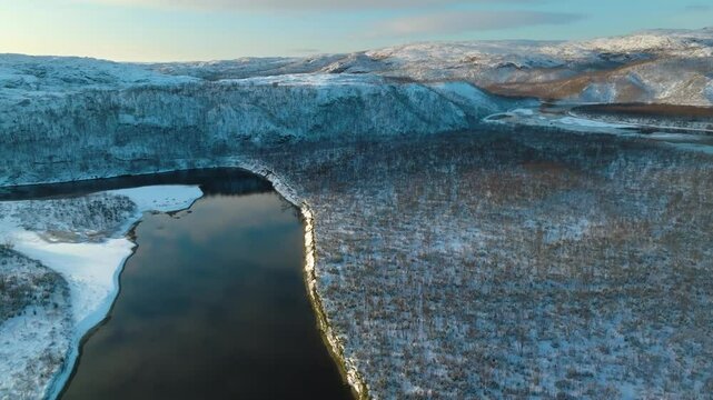 Majestic winter aerial of the Titovka River winding through a pristine snowy forest in Kola Peninsula, Russia, showcasing serene Arctic beauty and icy wilderness