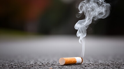 Close-up of an extinguished cigarette on asphalt with smoke, symbol of quitting smoking, layout with copy space