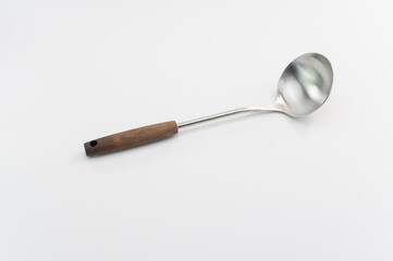 Immagine raffigurante un ramaiolo in acciaio con manico in legno su superficie bianca