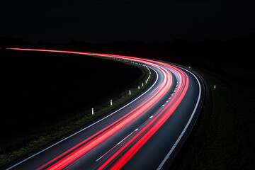 Swift traffic moves along a curving road at night with blurred light trails