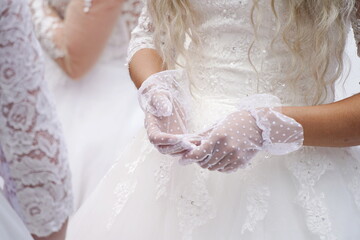 The bride in a white dress and lace gloves.