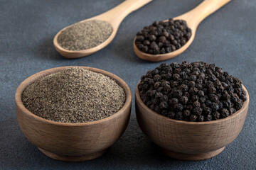 Ground black pepper with grains of black pepper on gray background
