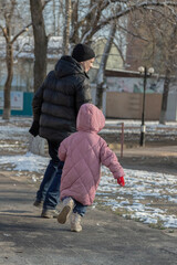 Grandfather playing with her granddaughter on the playground in the park in winter