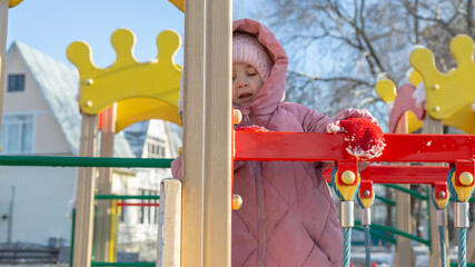 Two little girl playing on the playground on a winter day