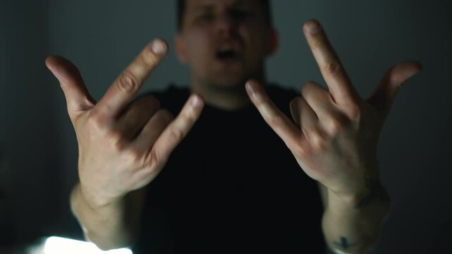 A man in black clothes shows a hand gesture.
Rock gesture.
Rock musician shows the rock'n'roll gesture.
Sign arm rock'n'roll.
rock, punk, culture, musician, ubculture