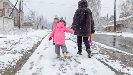 Little girls walking with his grandmother in the snow in winter