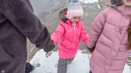 Grandmother and girls walk along a snowy street in winter