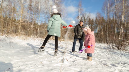 Playful family enjoying snowball fight in snowy winter park