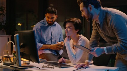 Multiracial team business colleagues Caucasian Indian men woman businessmen businesswoman cooperate work in night office diverse co-workers discuss computer project together IT company help employee