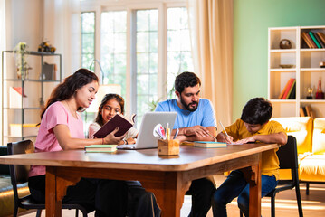 Parents teaching kids at home using laptop and books during study session in living room