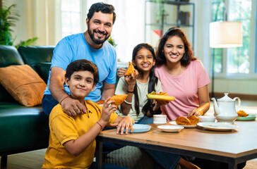 Family enjoying evening tea with samosa, sharing laughter and fried snacks in modern living room