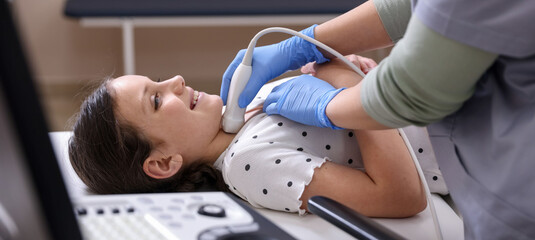 Sonographer conducting girl's thyroid gland ultrasound examination in clinic, closeup