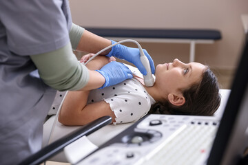 Sonographer conducting girl's thyroid gland ultrasound examination in clinic, closeup
