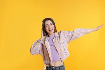 Vitrage gordijnen Happy woman in headphones dancing on yellow background © New Africa