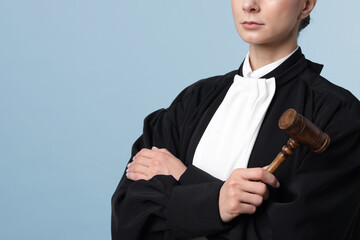 Judge with mallet on light blue background, closeup. Space for text