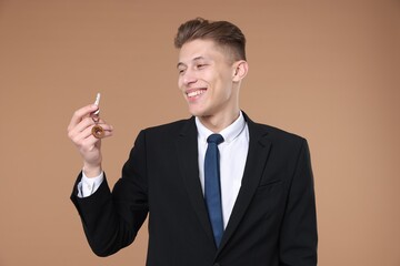 Real estate agent holding key with house shaped keychain on beige background