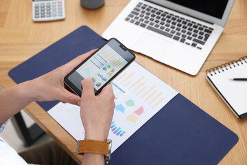 Man taking photo of document using scanning app on smartphone at desk in office, closeup