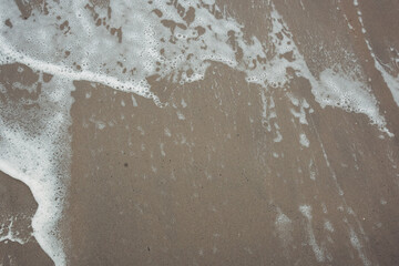 A beach with a large wave crashing onto the shore