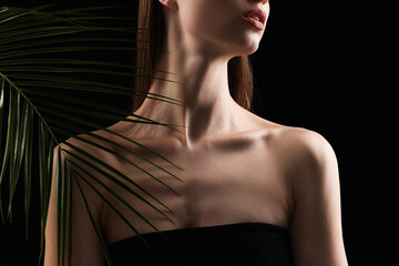 Woman with palm leaf on black background, closeup