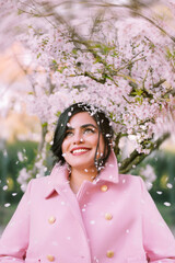 Portrait of a woman in pink coat under cherry blossoms in spring