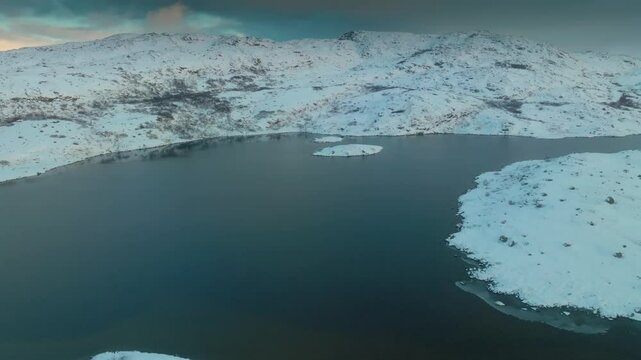 Expansive aerial footage of a frozen lake amid snow-laden terrain at Musta - Tunturi Ridge showcasing Arctic wilderness in northern Russia.