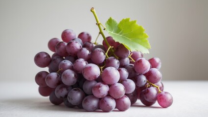 Fototapeta premium A Bunch of Fresh, Ripe, and Juicy Red Grapes with a Vibrant Green Leaf Detail