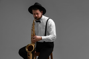 Naklejka premium Professional musician playing saxophone on grey background