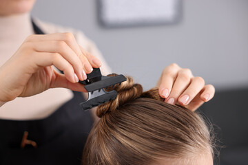Fototapeta premium Hairdresser doing girl's hairstyle in salon, closeup