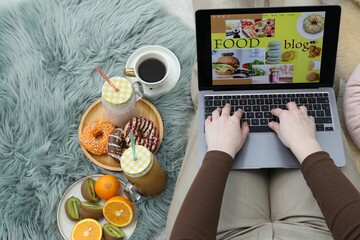 Blogger using laptop with food blog web site on floor indoors, above view