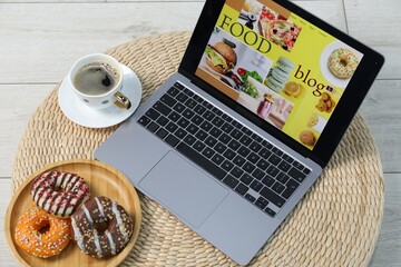 Laptop with food blog web site, coffee and donuts on floor indoors, above view