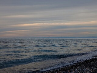 Sunset over the sea. Serene sea view with soft waves meeting a quiet pebble beach.
