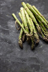 Bunch of fresh green asparagus on black surface